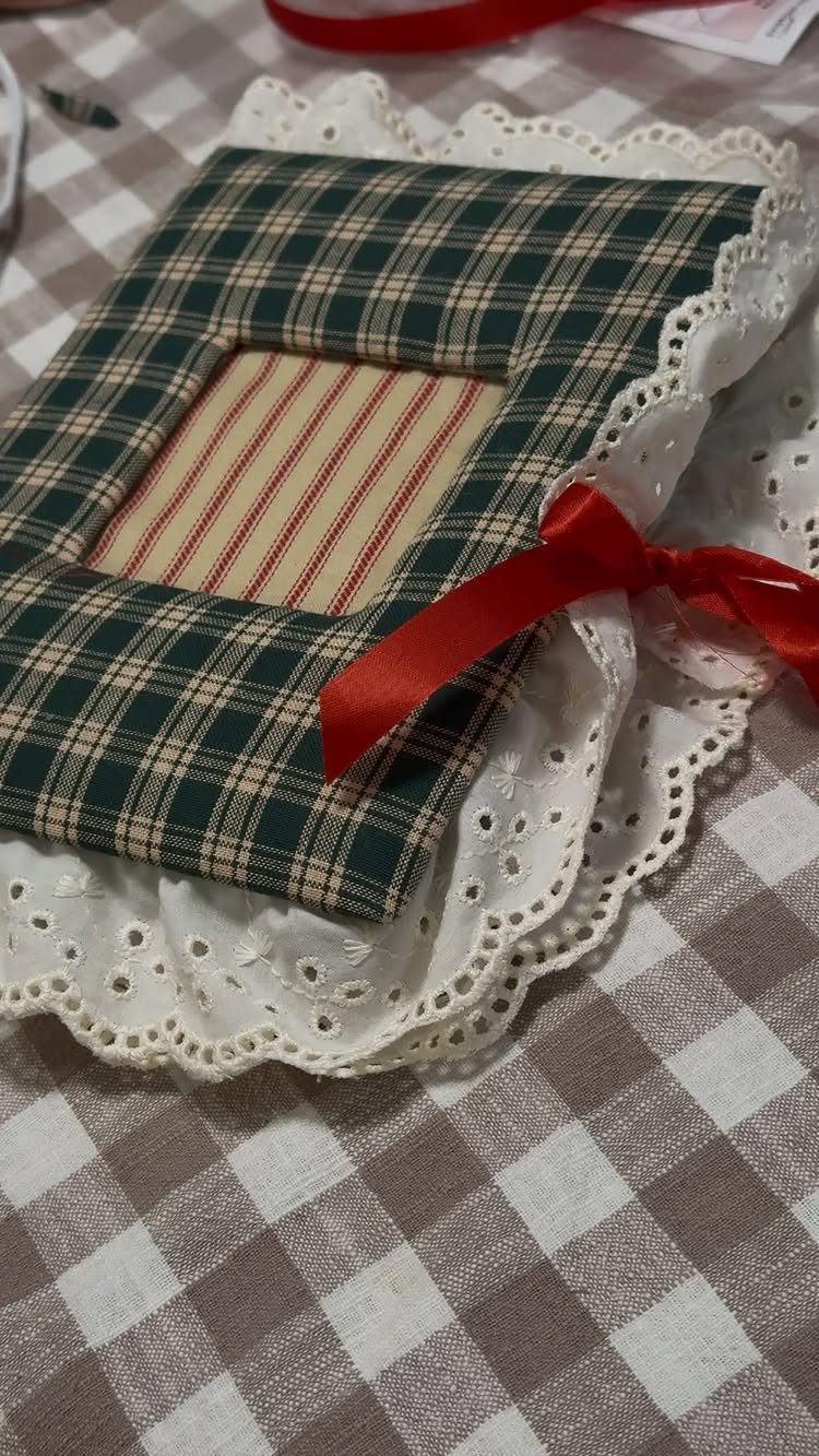 Handmade plaid fabric photo album with a red bow on a lace doily.