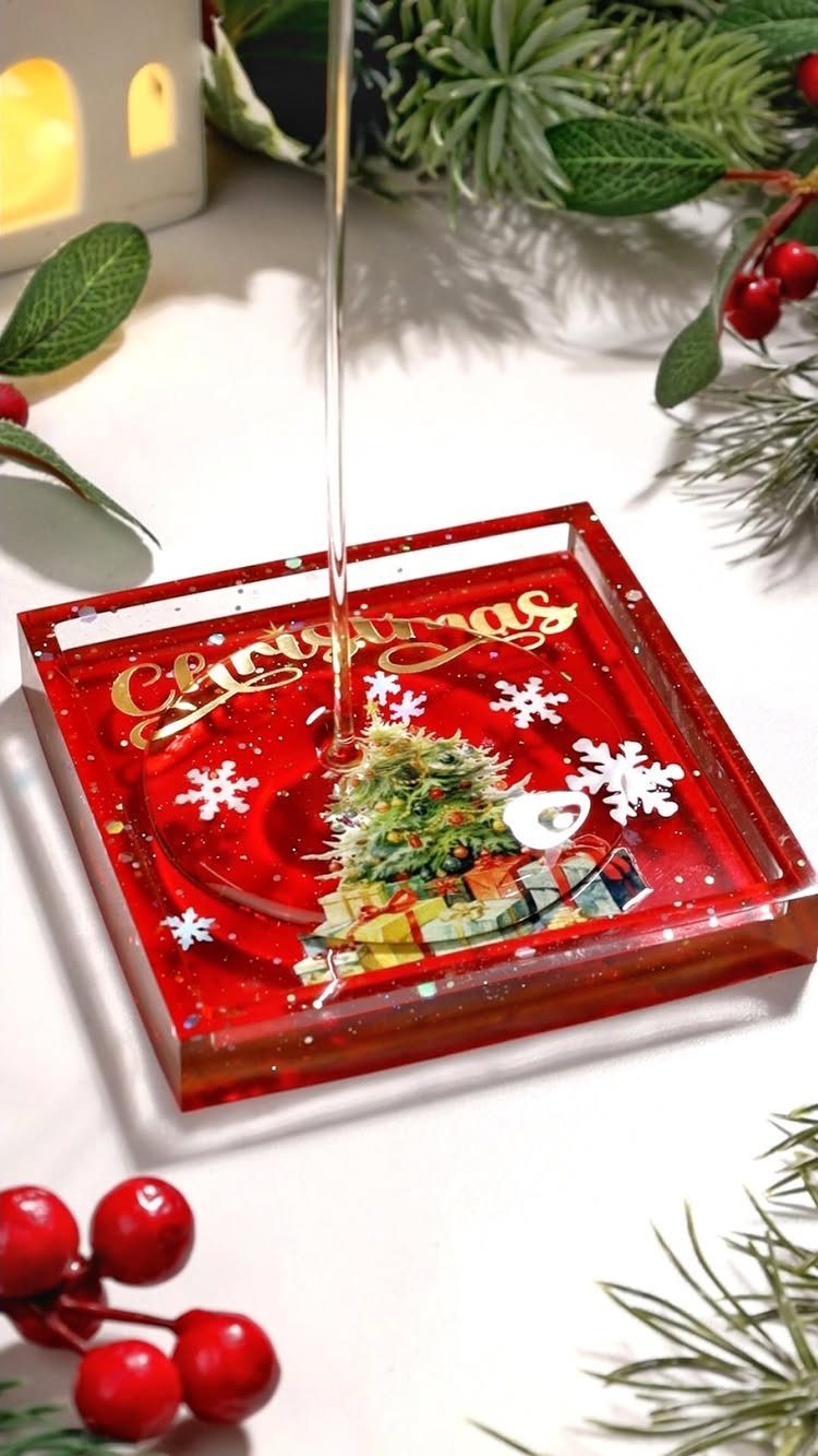 Red resin Christmas coaster with a tree design and water pouring over it.