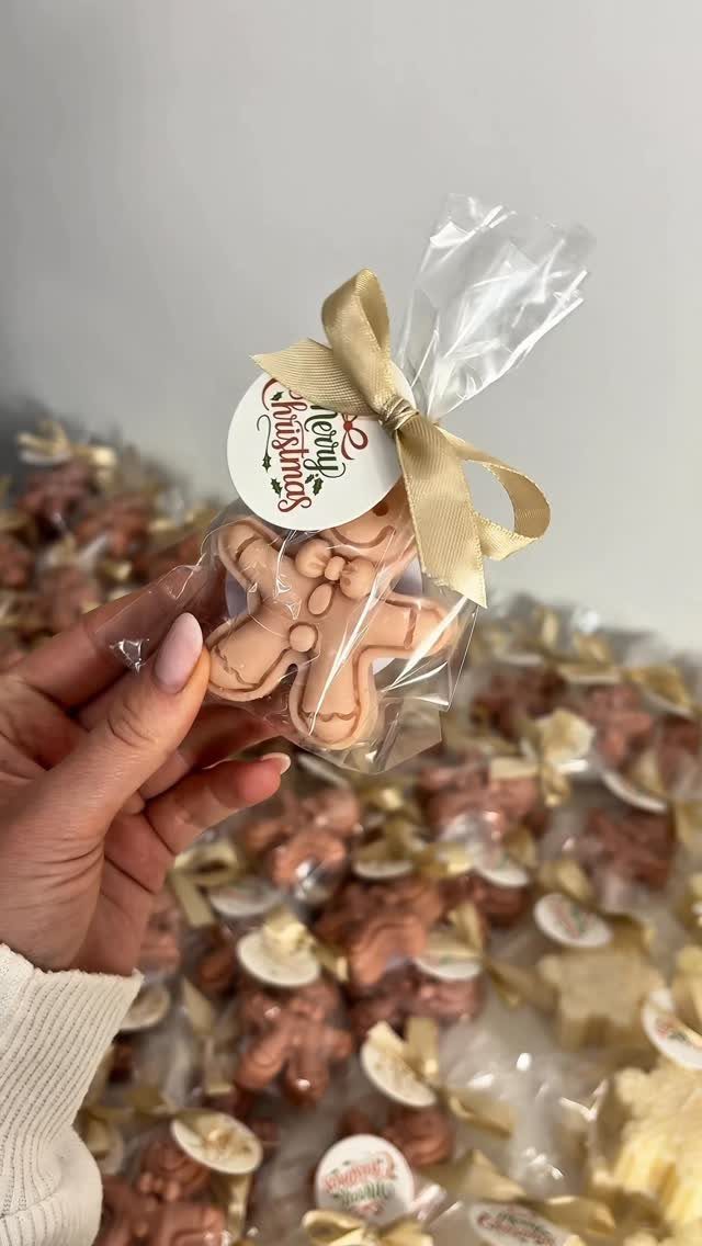 Gingerbread man cookie in a clear bag with gold ribbon and Christmas tag.