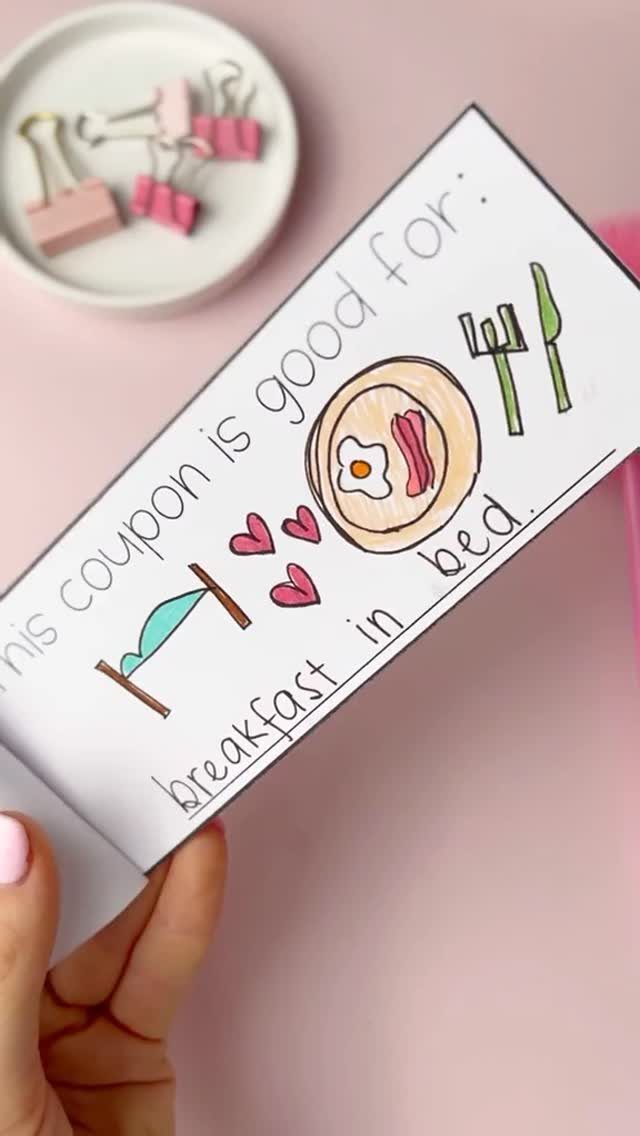 Handmade coupon for breakfast in bed with colorful drawings on a pink background.