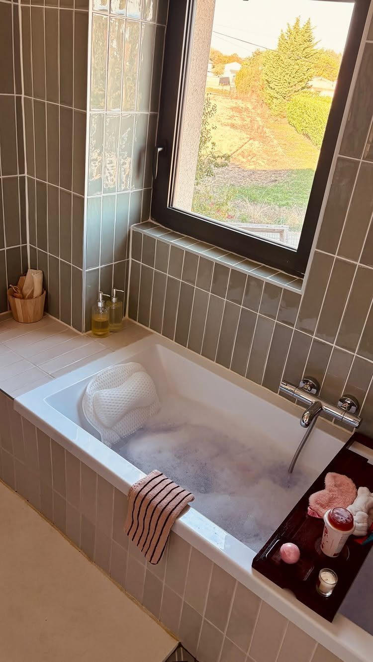 Bubble bath setup with a bath pillow, striped towel, and wooden caddy tray.