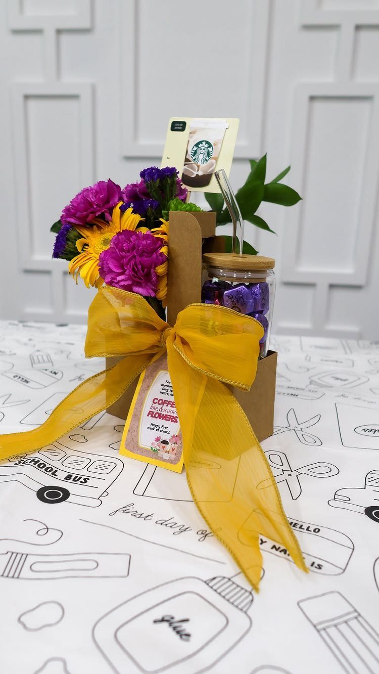 Gift set with flowers, candies, and a Starbucks gift card tied with yellow ribbon.