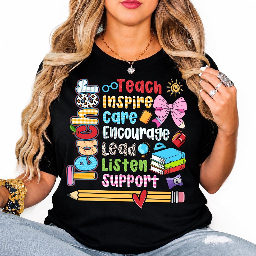 Woman wearing a black t-shirt with colorful teacher-themed text and school supply graphics.