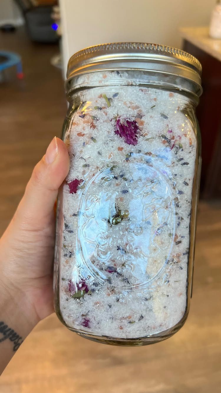 Glass mason jar filled with white bath salts and dried flower petals