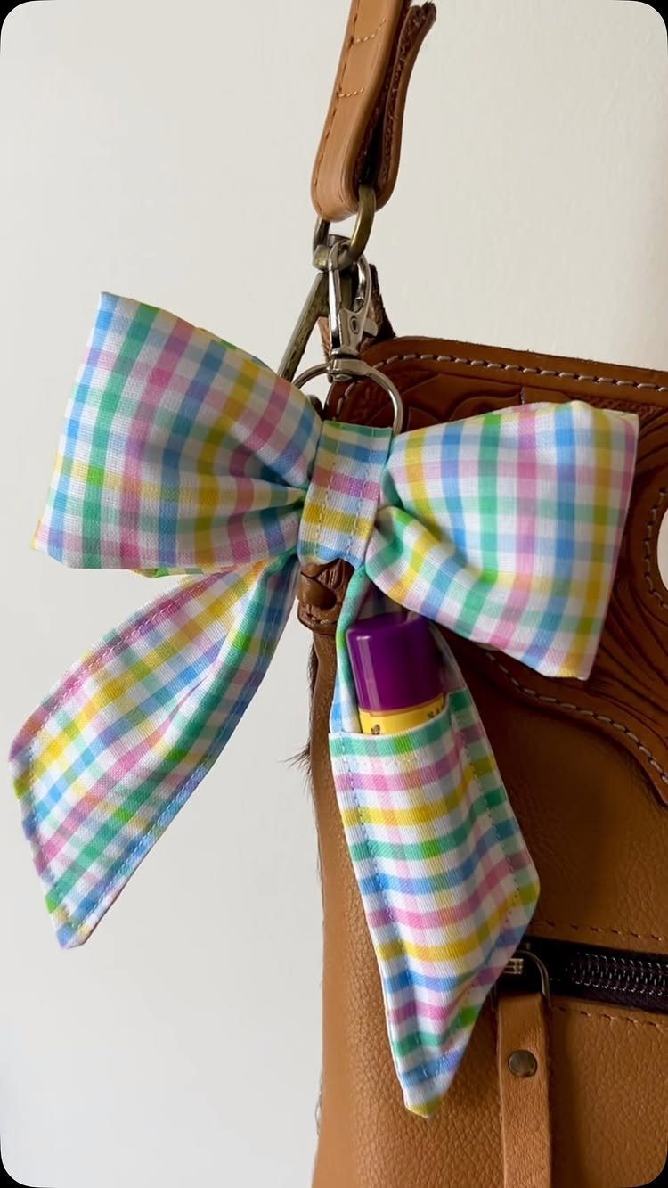 Pastel plaid bow keychain holder with lip balm attached to a brown bag