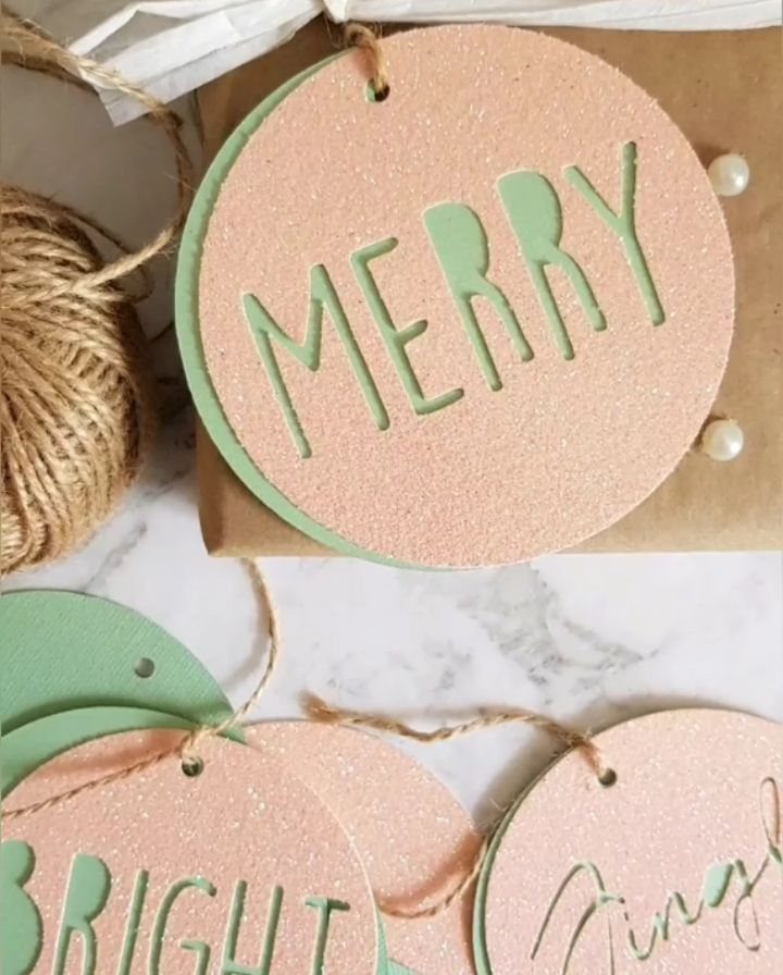 Kraft paper wrapped gifts with glittery circular tags and twine on marble.