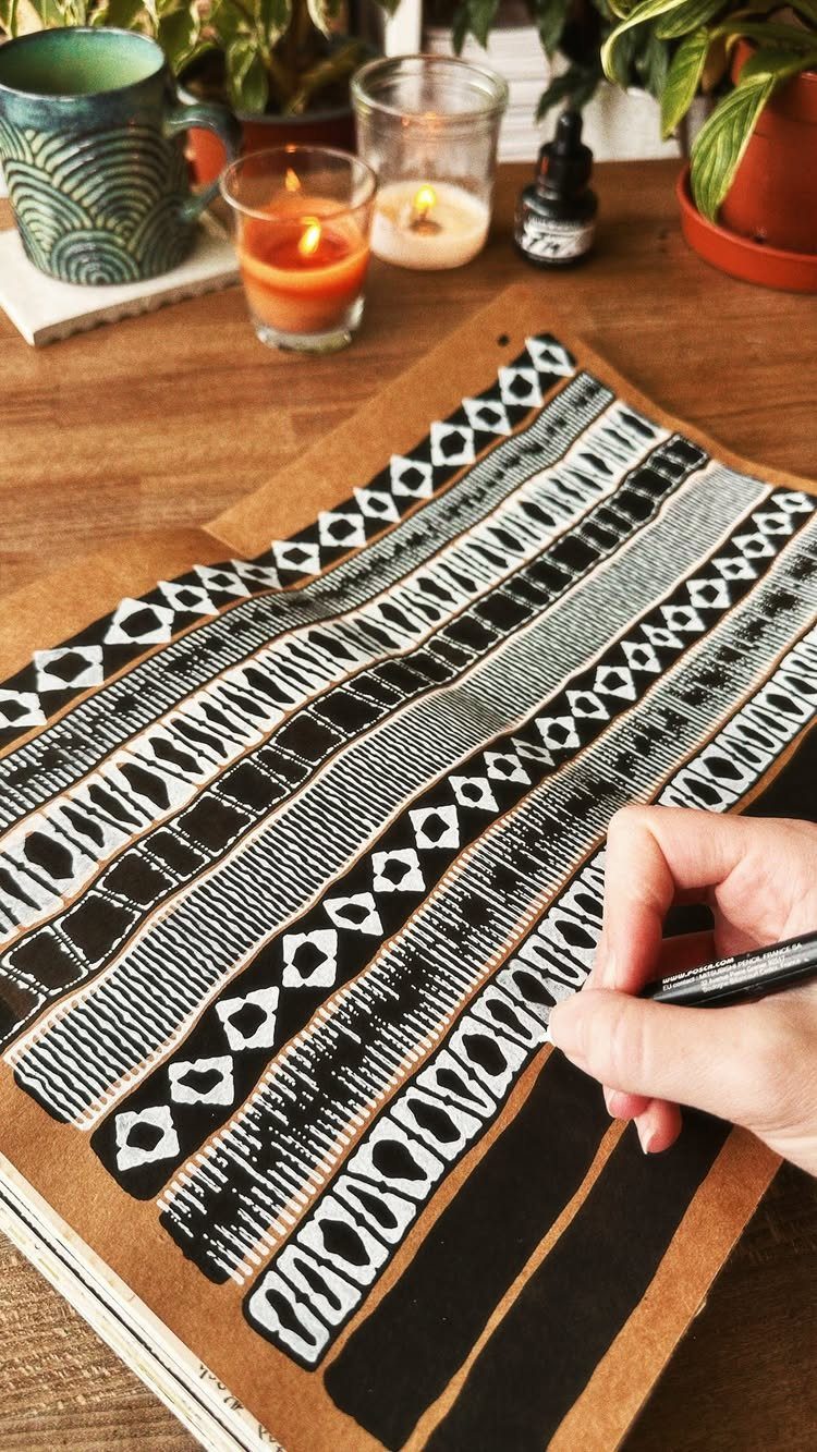 Hand drawing black geometric patterns and stripes on brown kraft paper wrapping.