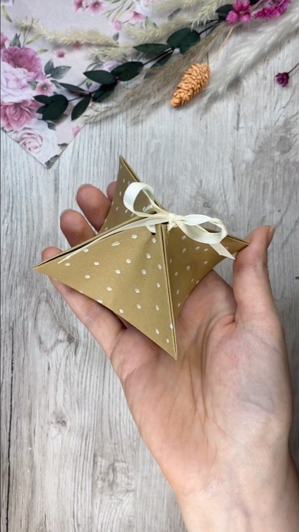 Star-shaped brown kraft paper gift box with white dots and white ribbon bow.