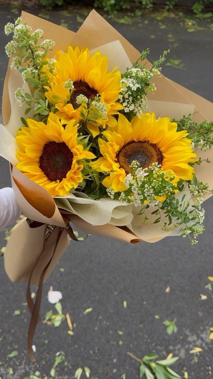 Sunflowers and white flowers wrapped in brown kraft paper tied with a ribbon.