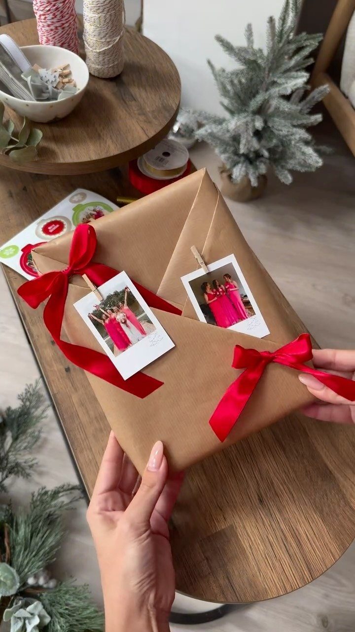 Kraft paper wrapped gift with red ribbons and polaroid photos attached with clips.