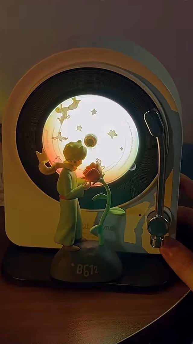 Small white record player with a Little Prince figurine holding a red rose.