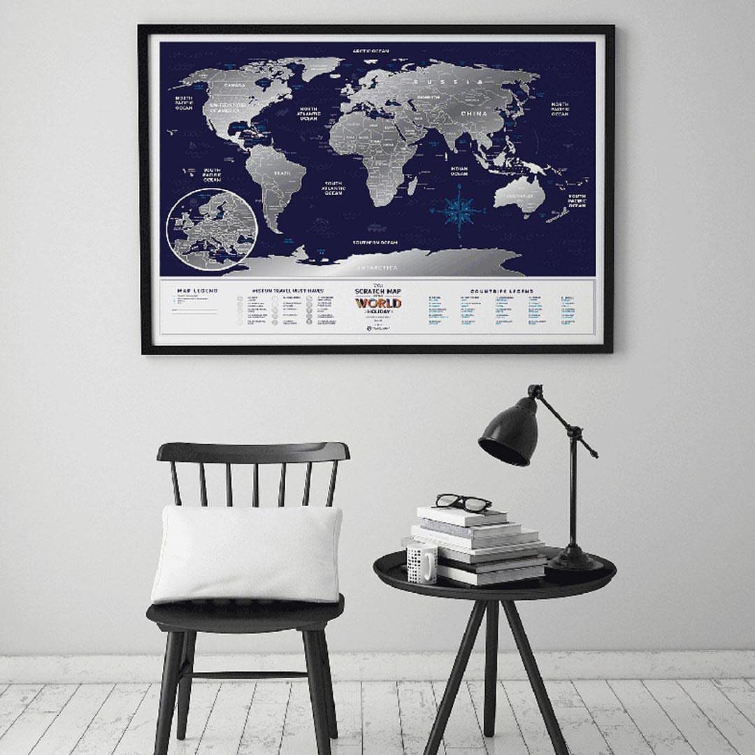 Framed scratch-off world map hanging above a black chair and side table.