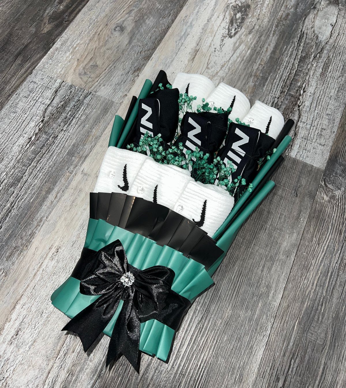 Nike socks arranged as a bouquet wrapped in green paper with a black bow.