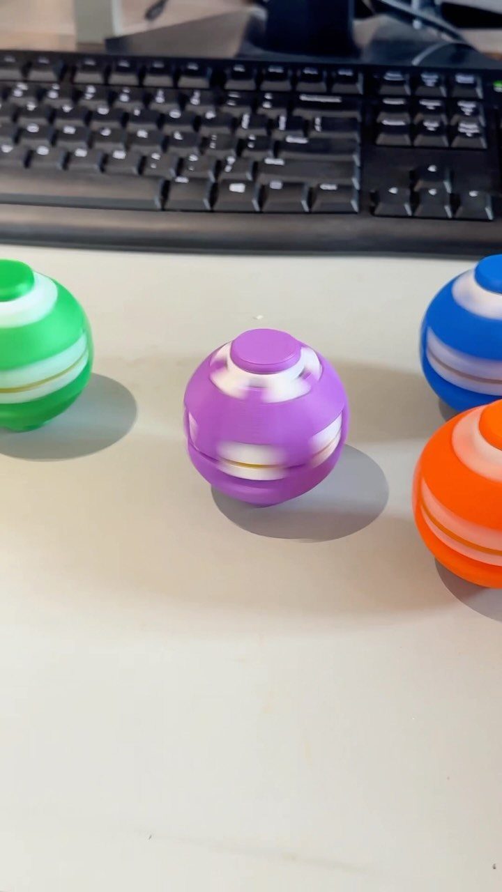 Colorful spherical stress balls on a white desk in front of a keyboard.
