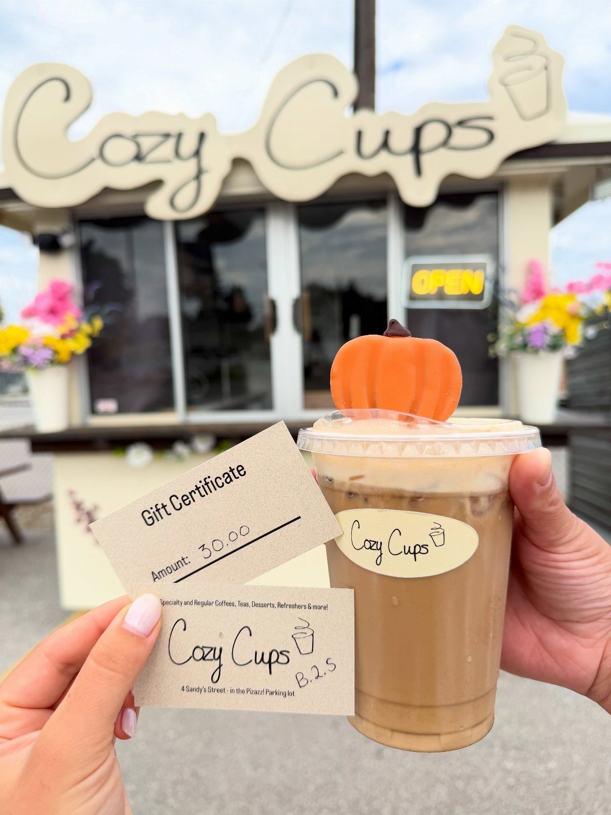 Hands holding a coffee shop gift certificate and an iced coffee drink.