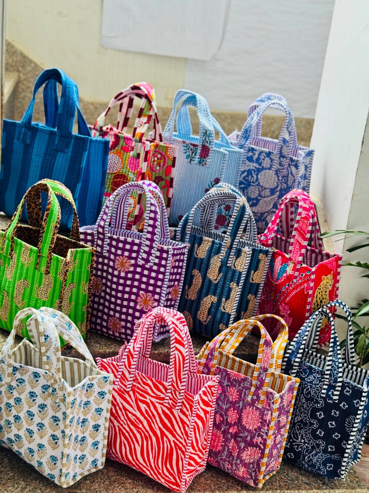 Small colorful fabric tote bags with various patterns arranged in rows.