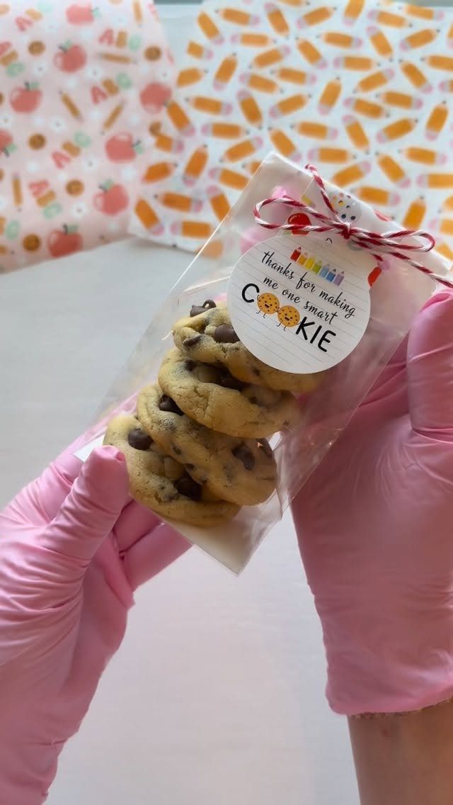 Chocolate chip cookies in a clear bag with a gift tag and pink gloves.