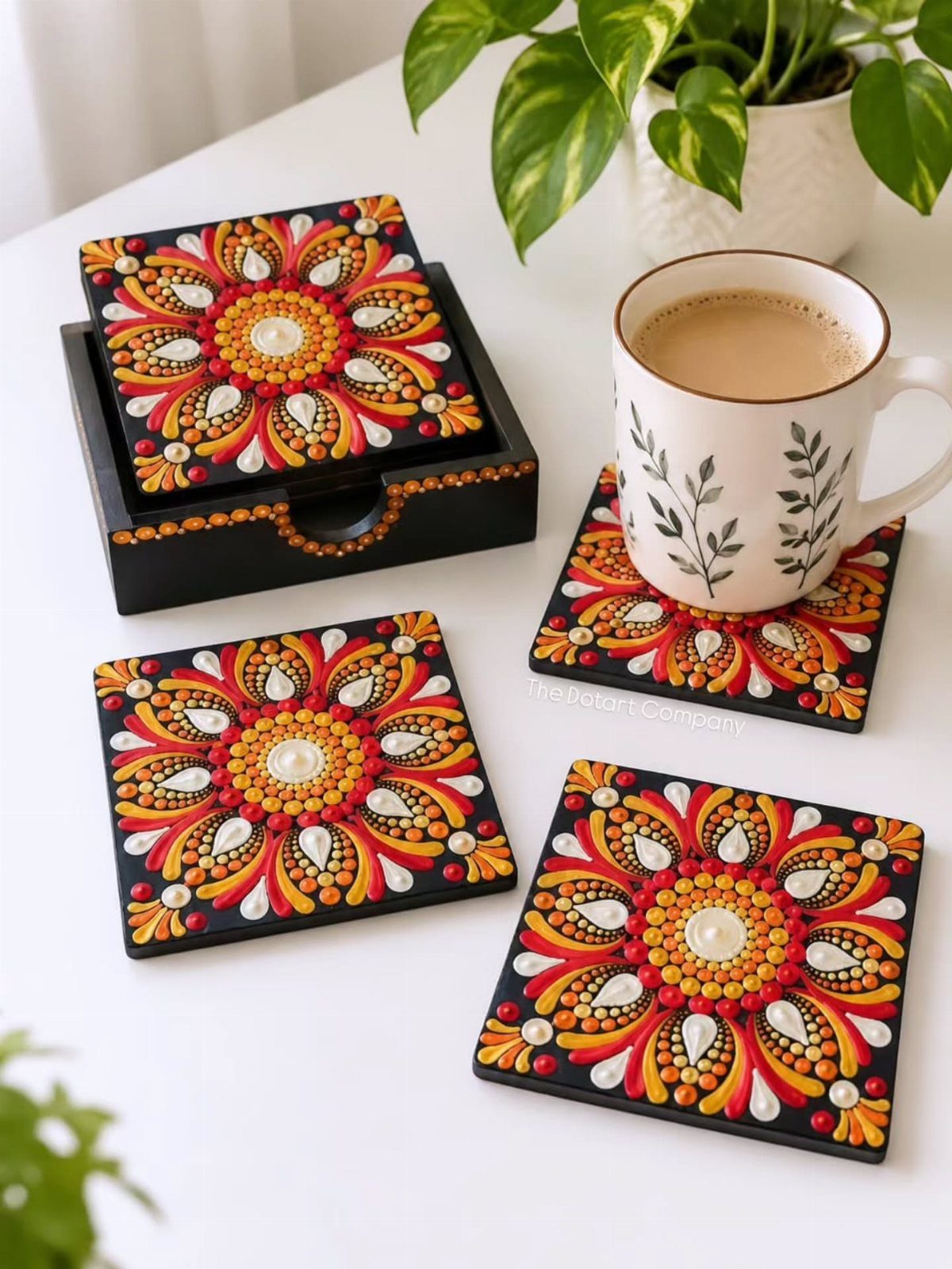 Hand-painted mandala dot art coasters with a coffee mug on a white table
