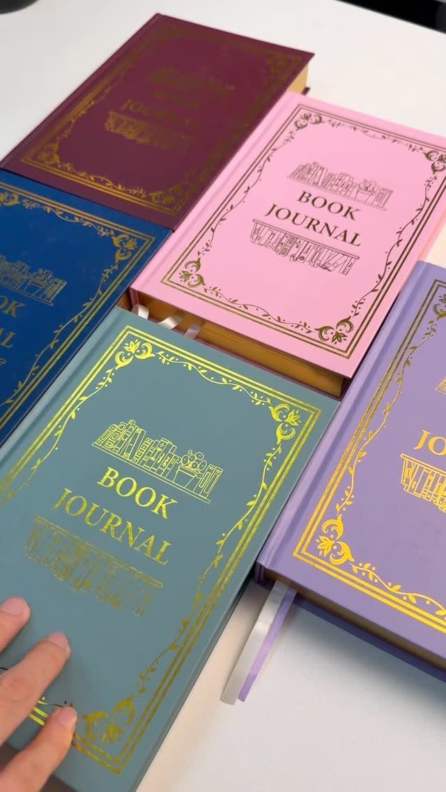 Colorful hardcover book journals with gold foil detailing arranged on a white surface.
