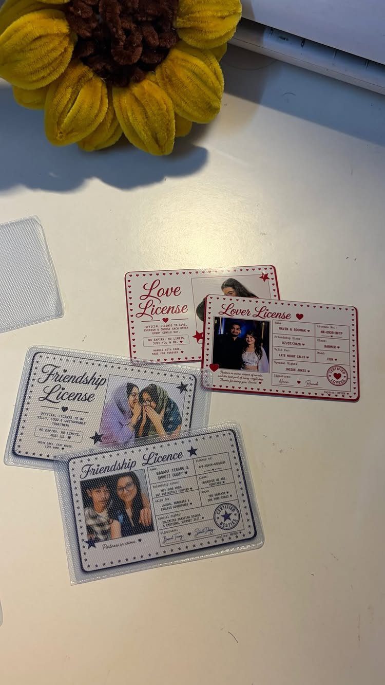 Customized love and friendship license cards with photos resting on a white surface.