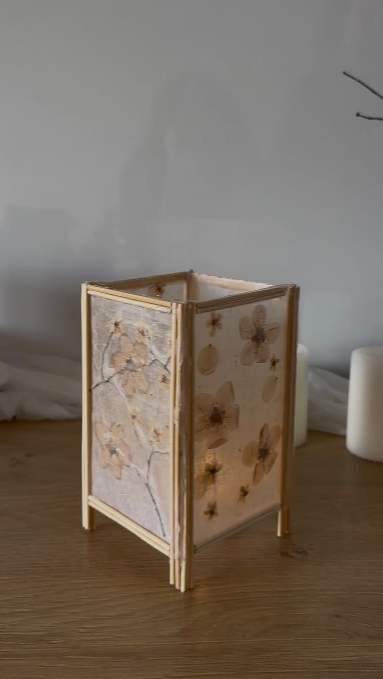 Wooden framed lantern with pressed dried flowers and a warm internal glow.