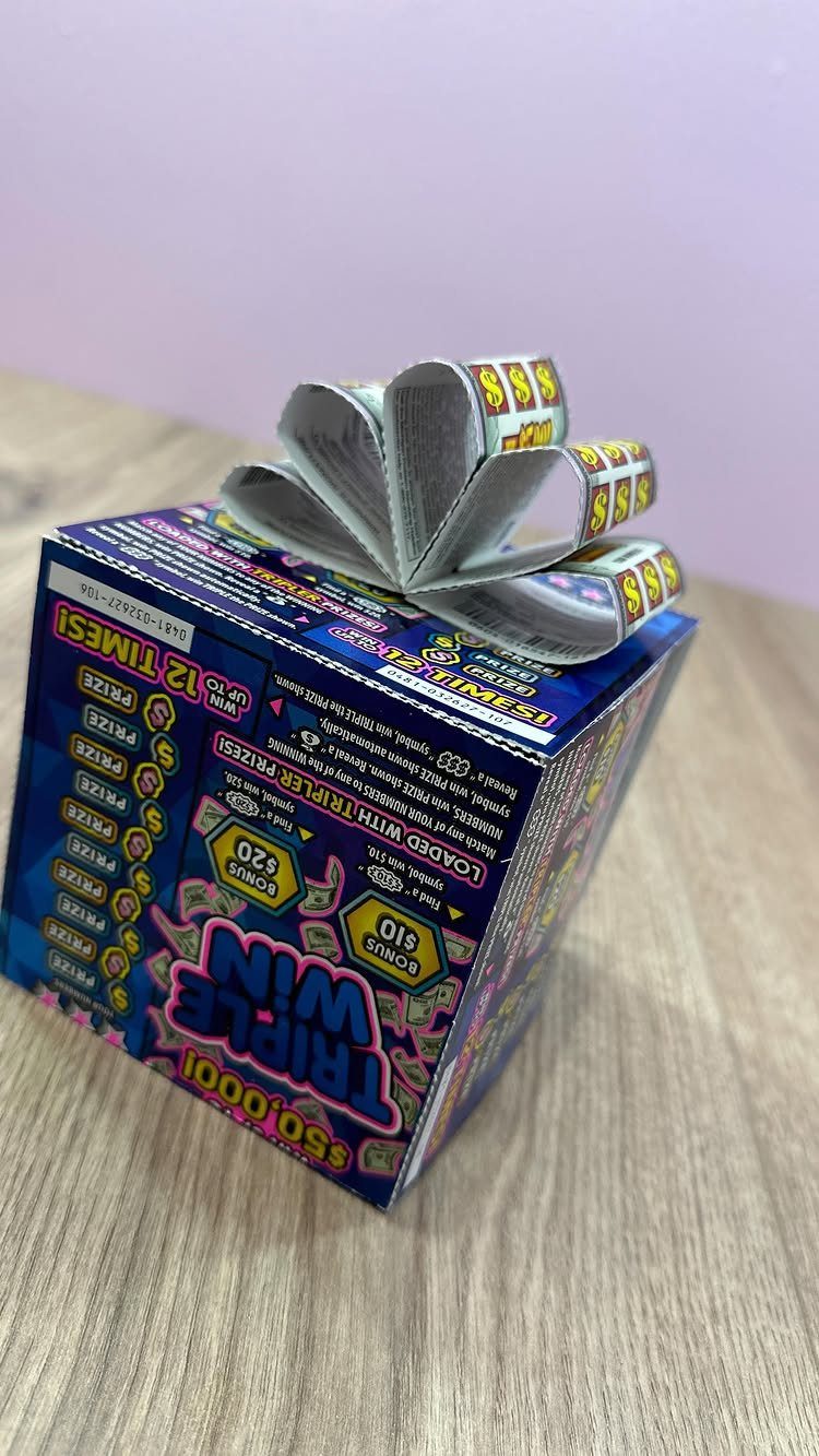 Lottery ticket box topped with a decorative bow made of folded dollar bills.