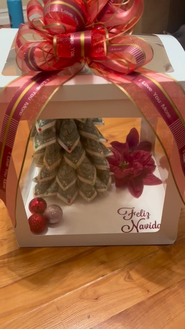 Money tree made of folded bills inside a white gift box with red ribbon