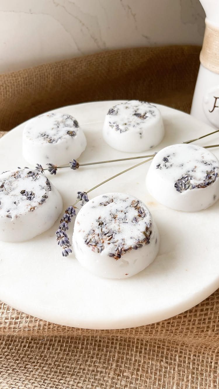 White round bath bombs with dried lavender on a white marble platter