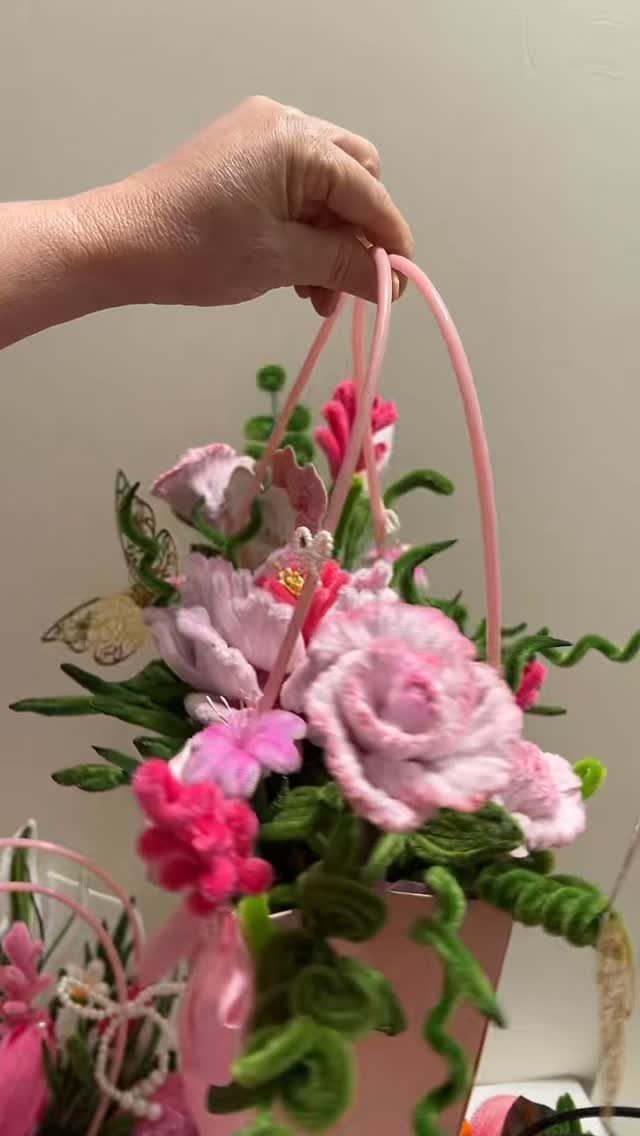 Pink basket filled with handmade fabric flowers held by a person's hand.