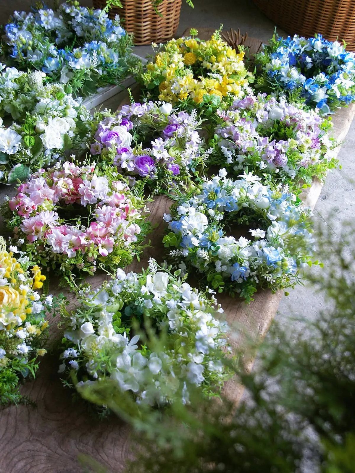 Small colorful floral wreaths arranged on a rustic wooden surface.