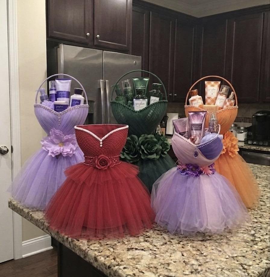 Dress-shaped gift baskets with tulle skirts filled with beauty products on a kitchen counter