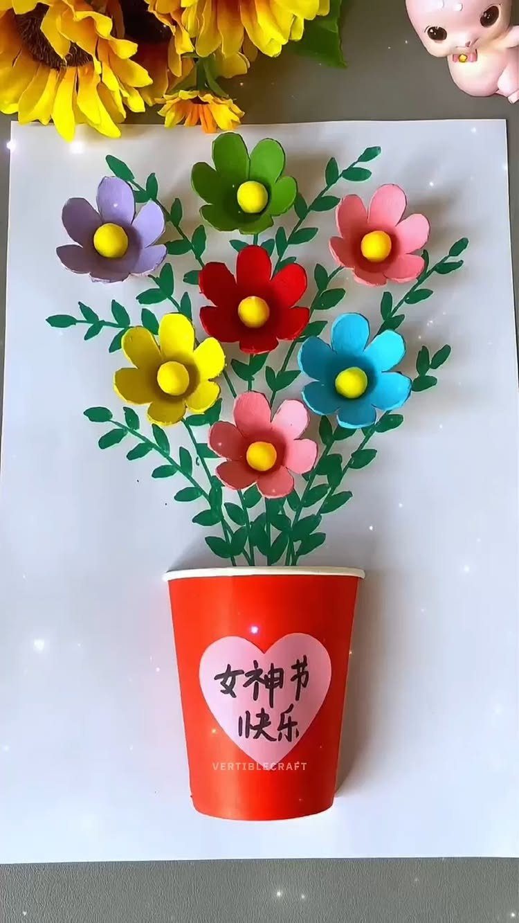 Egg carton flowers in various colors arranged in a red paper cup.