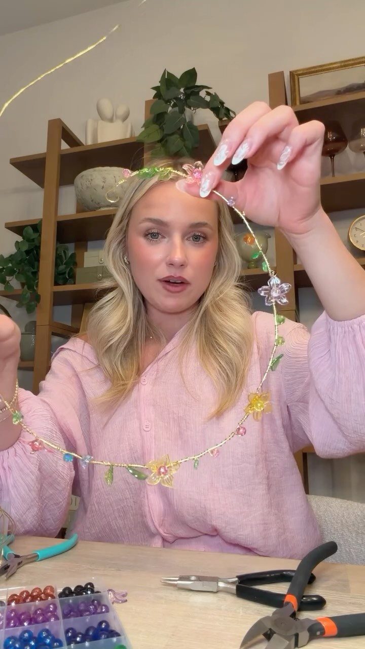 Woman holding a handmade floral wire crown with jewelry tools on a table