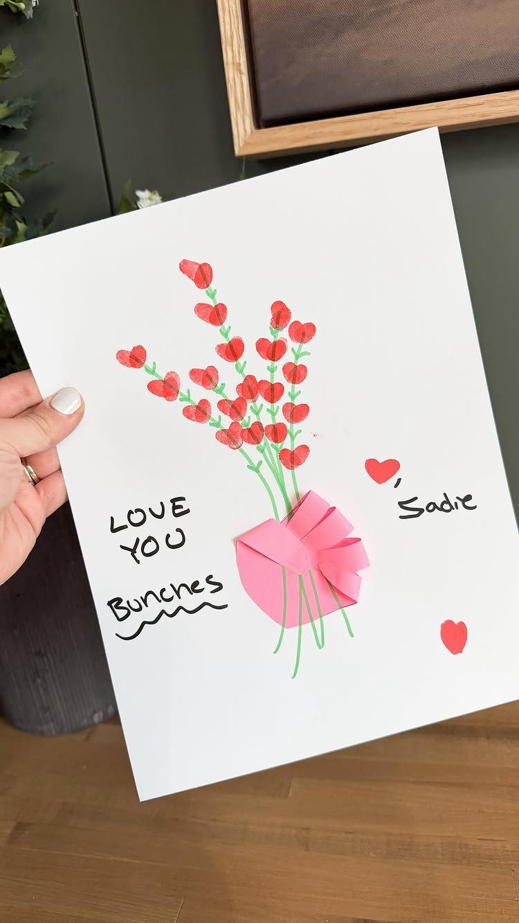 Handmade card with red fingerprint heart bouquet and pink paper bow on white paper