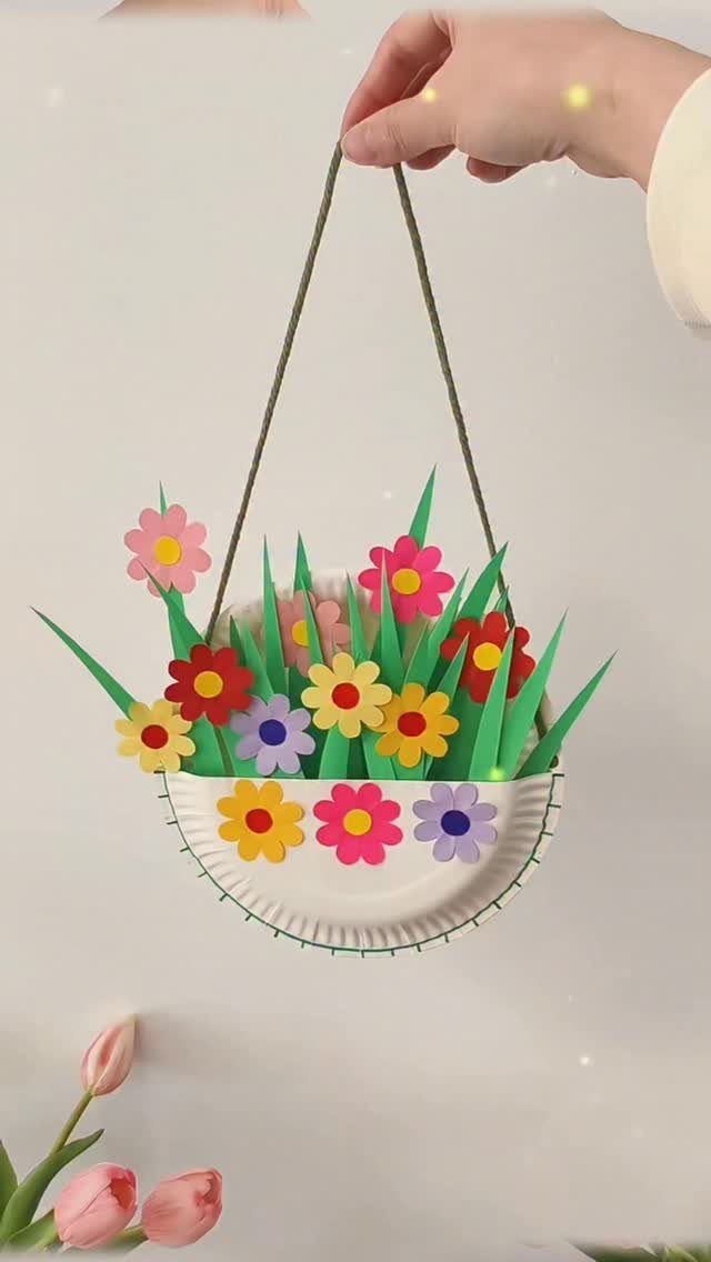 Paper plate basket craft with colorful paper flowers and green grass hanging by string