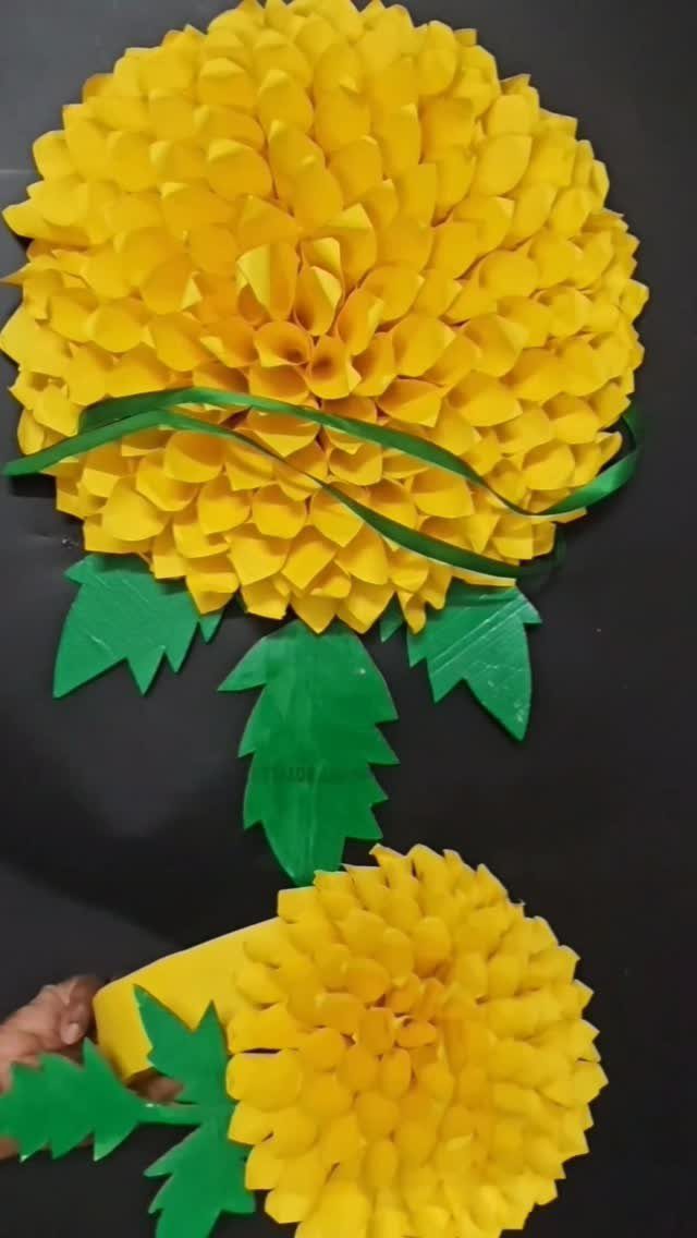 Yellow paper marigold flowers with green leaves on a black background