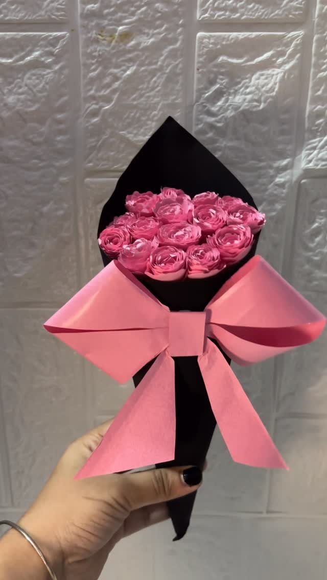 Pink paper rose bouquet wrapped in black paper with a large pink bow.