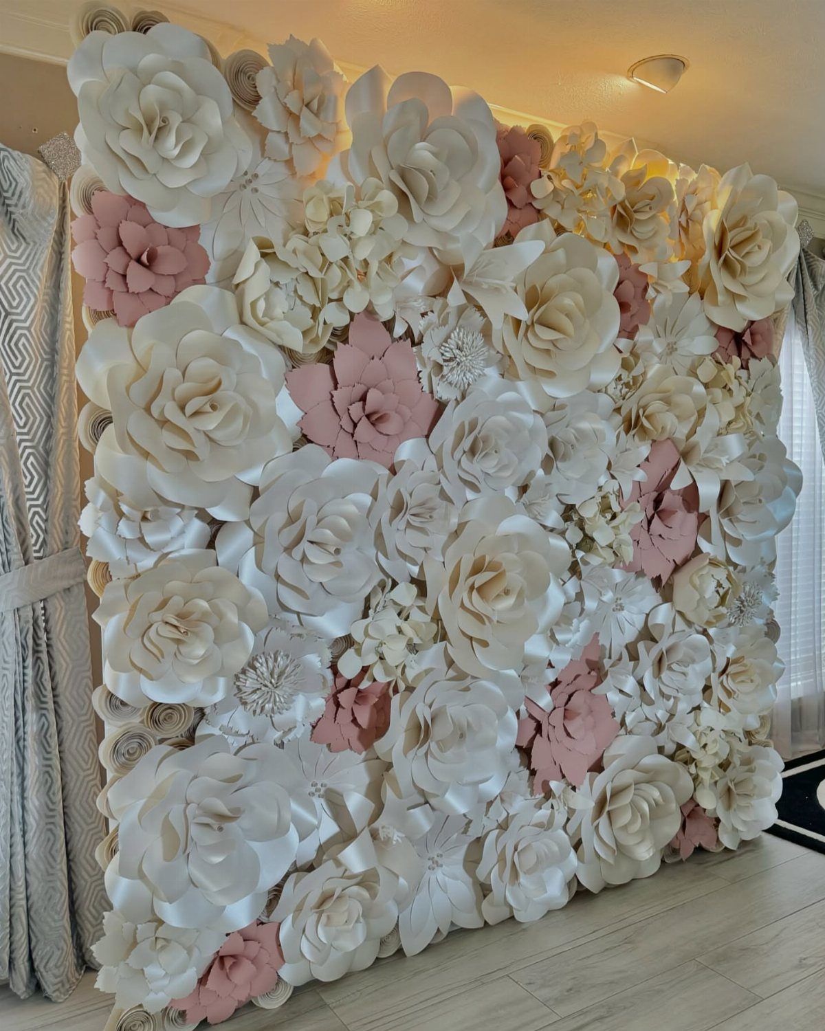 Large wall covered in oversized white and pink 3D paper flowers.