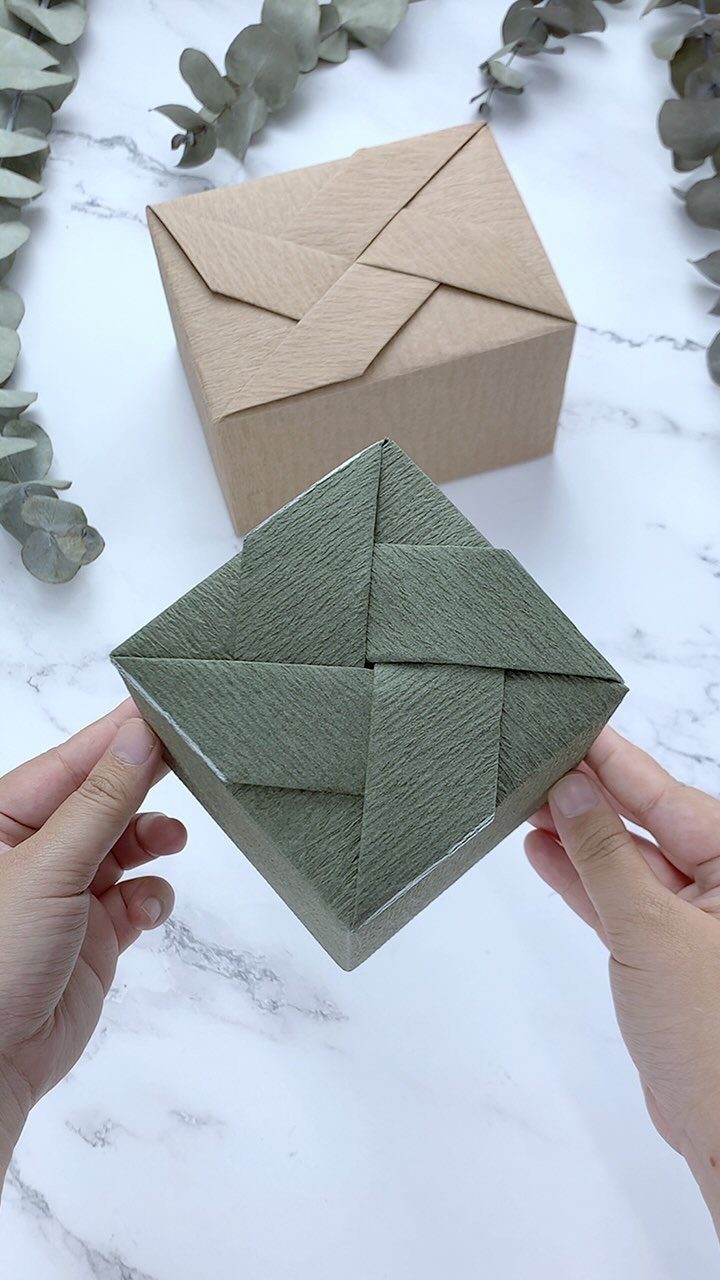 Two elegantly wrapped square gift boxes with precise creases on a marble surface.