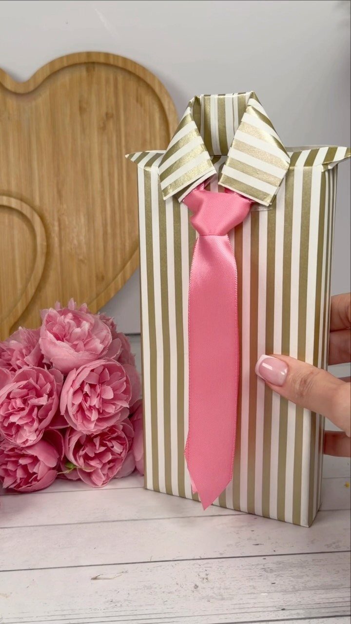 Gift wrapped in striped paper shaped like a shirt with a pink tie.