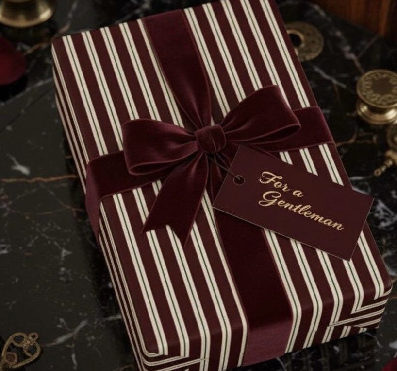 Striped burgundy gift box with a velvet bow and a gentleman's gift tag.