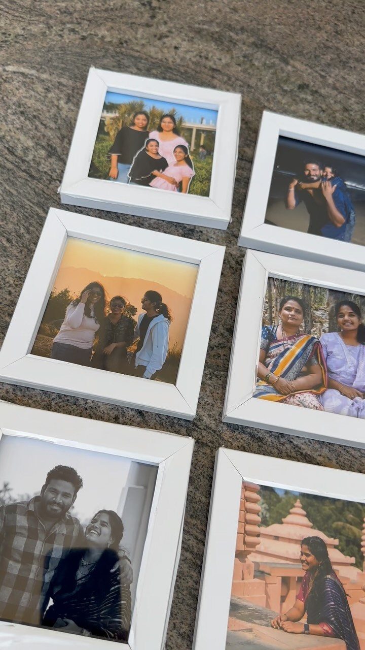 Six white picture frames with personal photos resting on a grey stone surface.