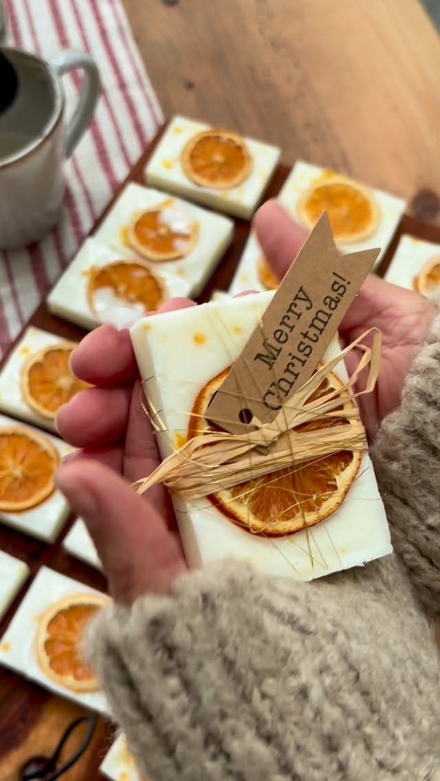 Handmade white soap bars with dried orange slices and Christmas gift tags.