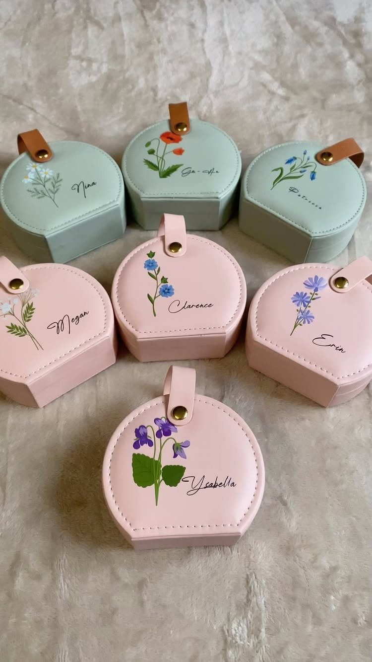 Small hexagonal jewelry cases in pink and mint green with floral designs and names.