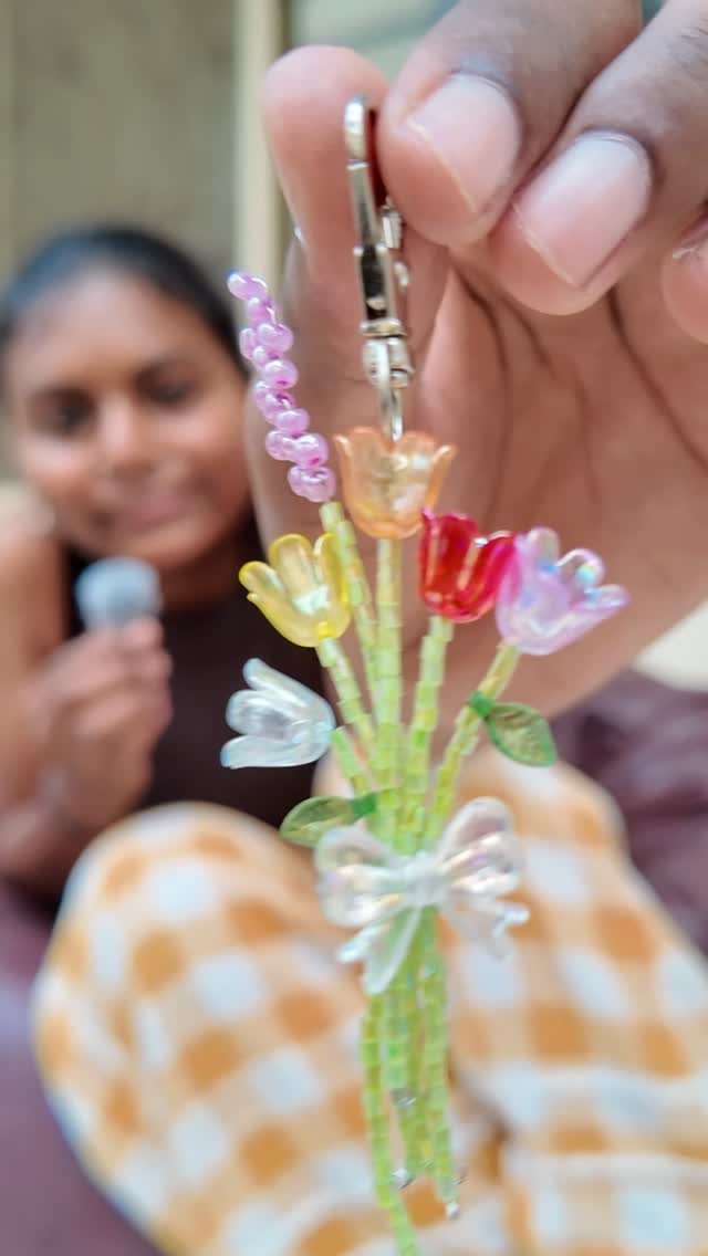 Beaded flower bouquet keychain held in a hand with a blurred person behind.