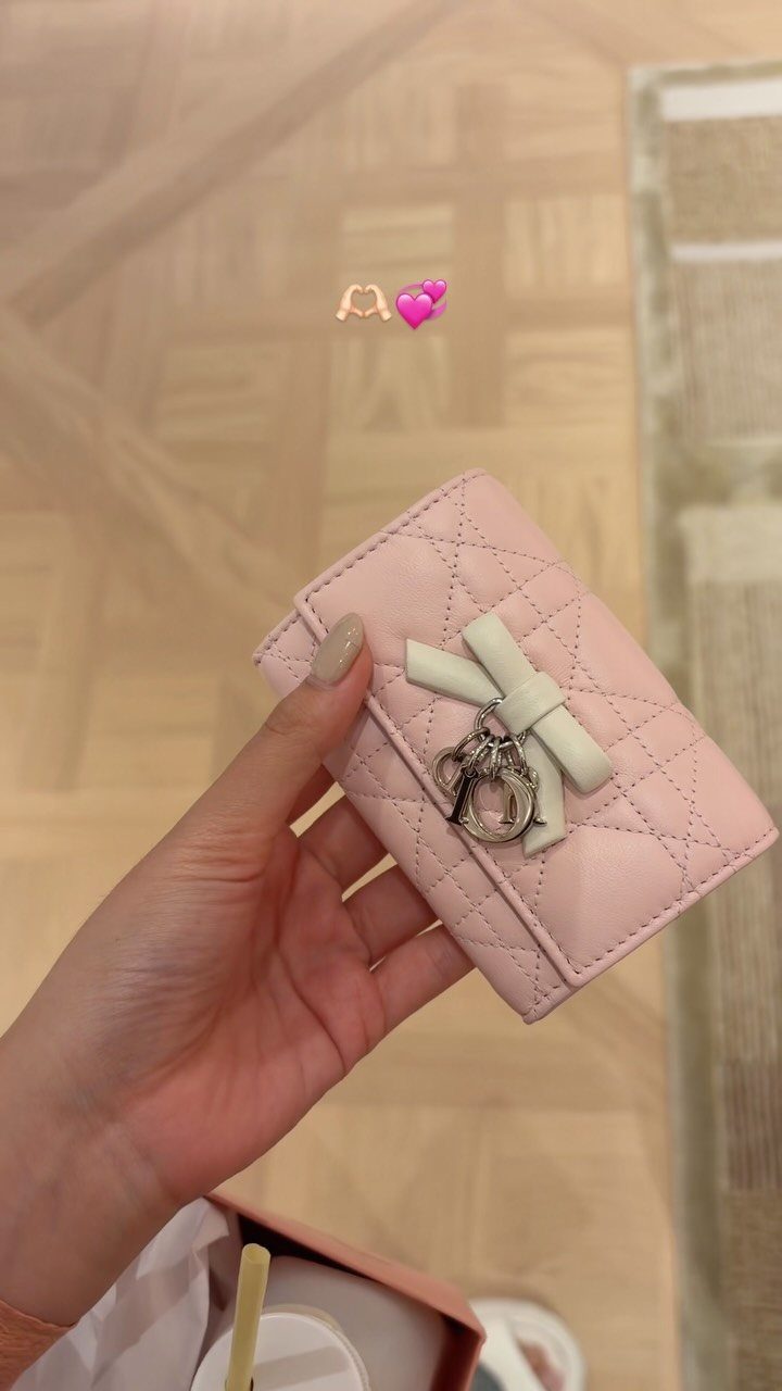 Small quilted pink leather wallet with a white bow and silver charm.