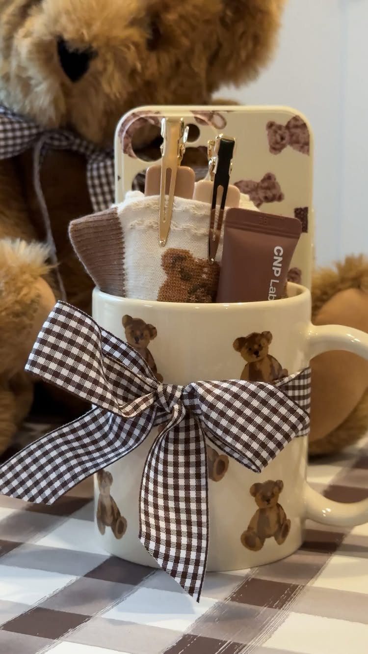 White teddy bear mug filled with skincare, hair clips, and socks as a gift.