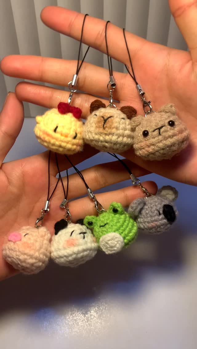 Seven small crocheted animal charms held in two open hands.