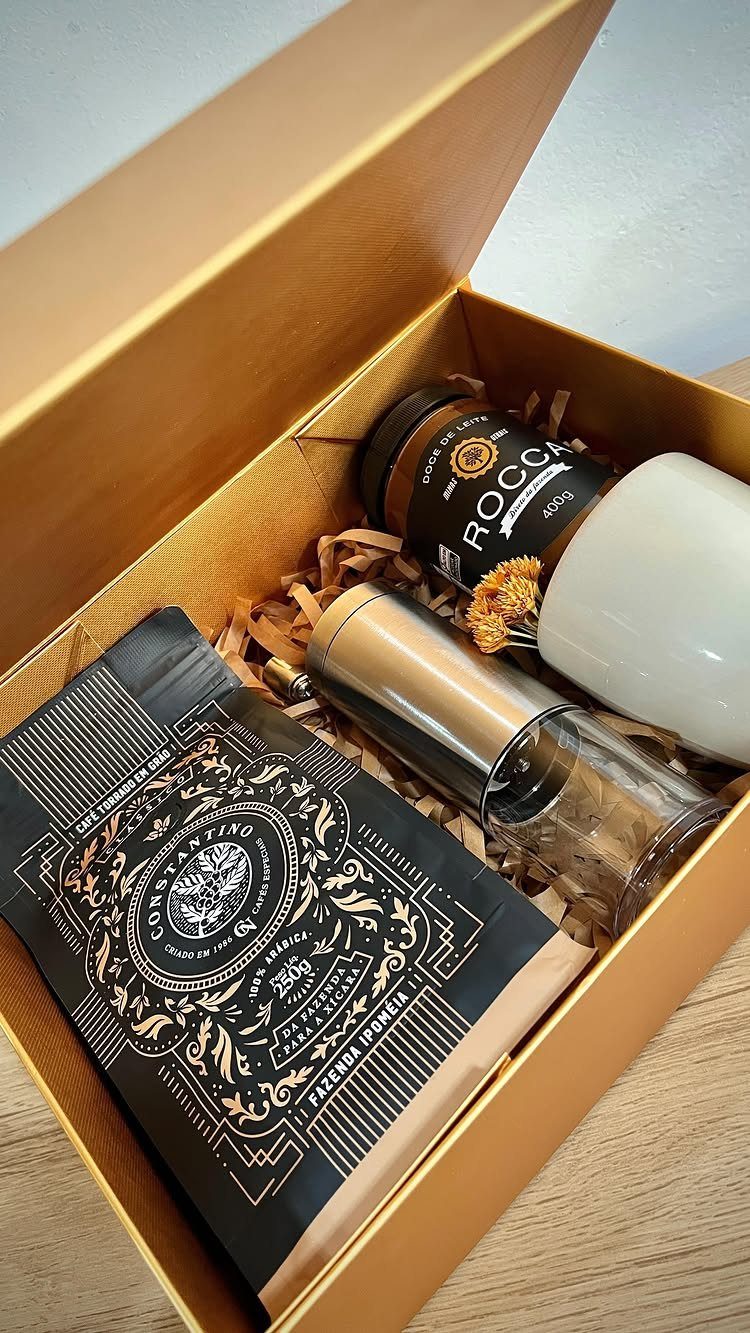 Gourmet coffee set in a gold box with beans, jar, and candle.