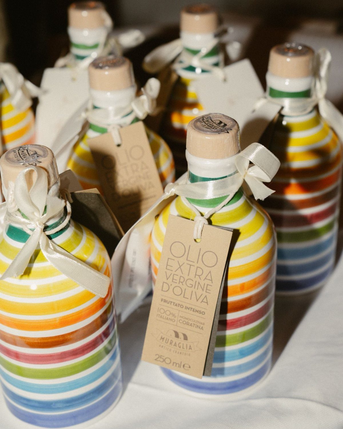 Rainbow striped ceramic olive oil bottles with white ribbons and brown gift tags.
